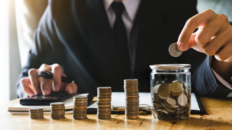businessman holding coins putting in glass with using smartphone and calculator to calculate  concept saving money for finance accounting